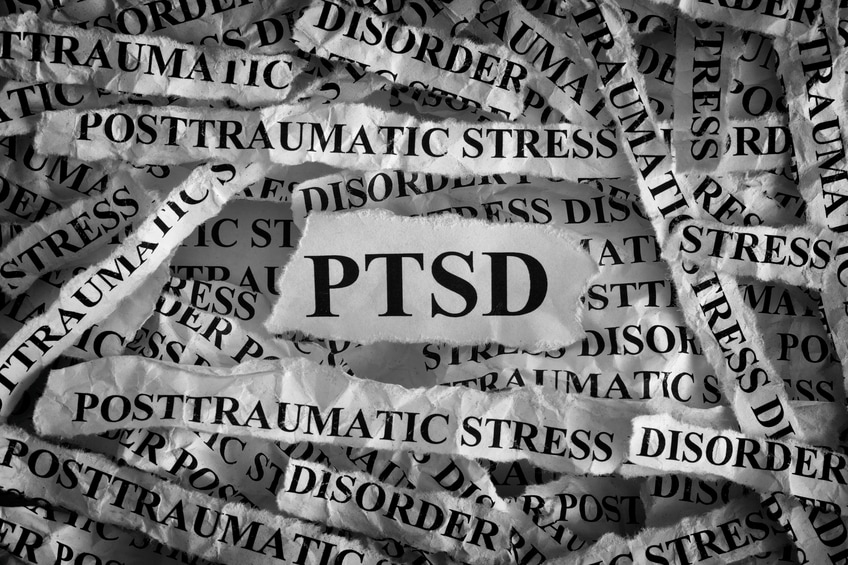 Collage of torn paper strips displaying the words PTSD and post-traumatic stress disorder, symbolizing mental health and trauma awareness.