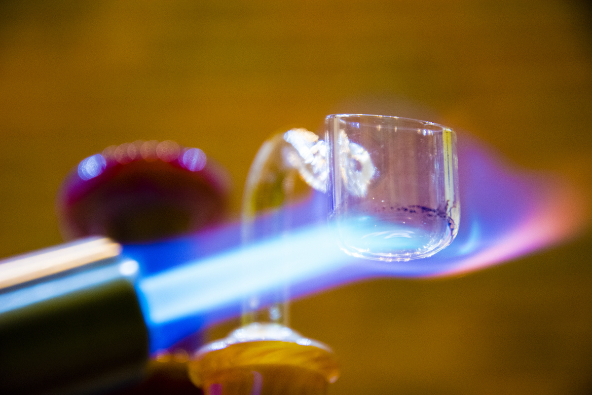 Close-up of a blowtorch flame heating a glass quartz banger used for dabbing cannabis concentrates.