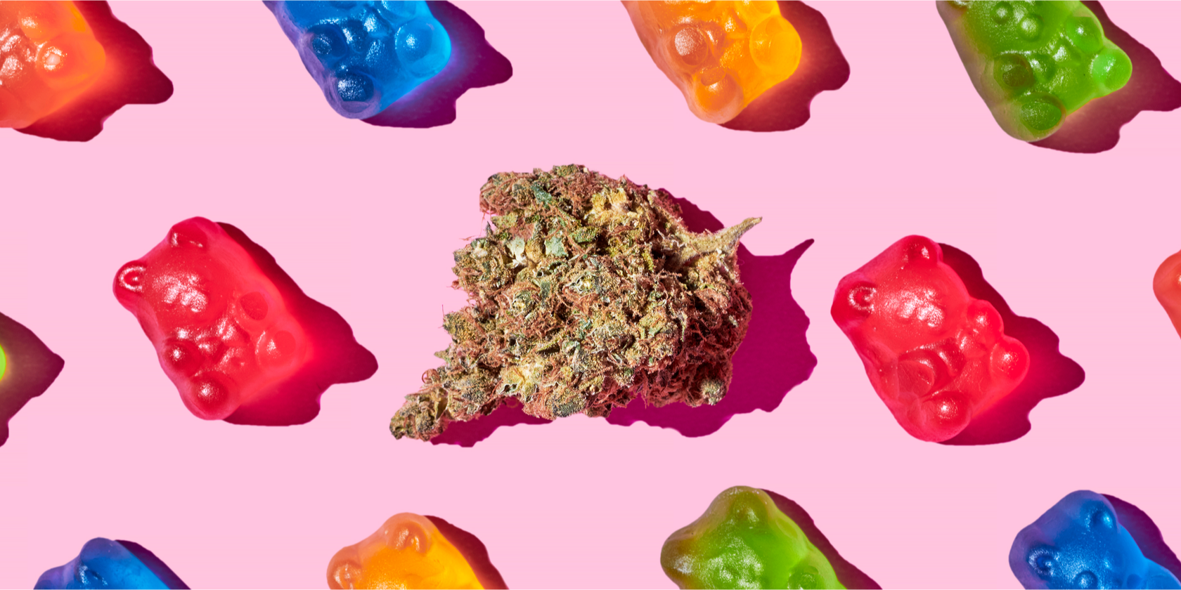 Cannabis bud centered on a pink background, surrounded by colorful gummy bear candies arranged in a repeating pattern.