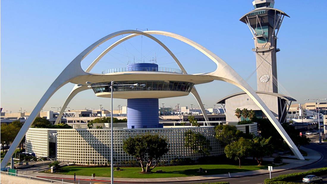 Theme Building and control tower at Los Angeles International Airport (LAX) under a clear blue sky.